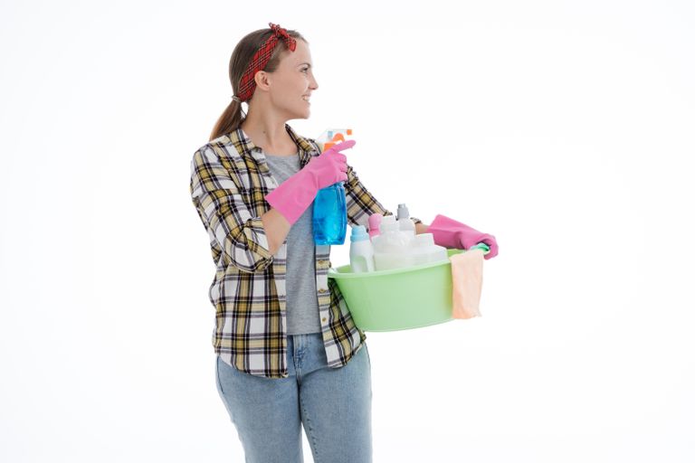 Woman holding cleaning supplies in a studio shot with a white background. Perfect for housekeeping themes.