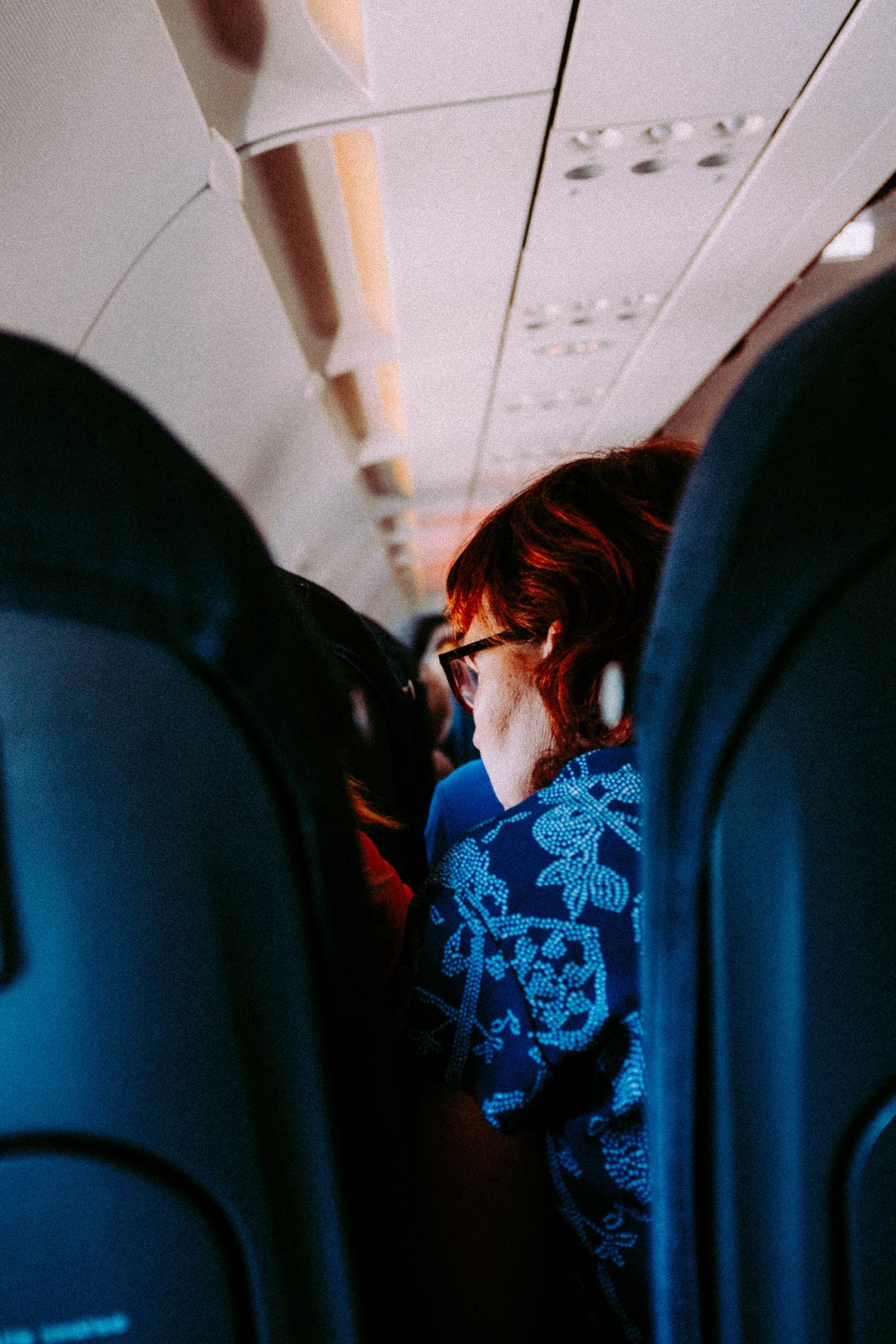 Woman sitting in an airplane cabin interior during daytime travel.