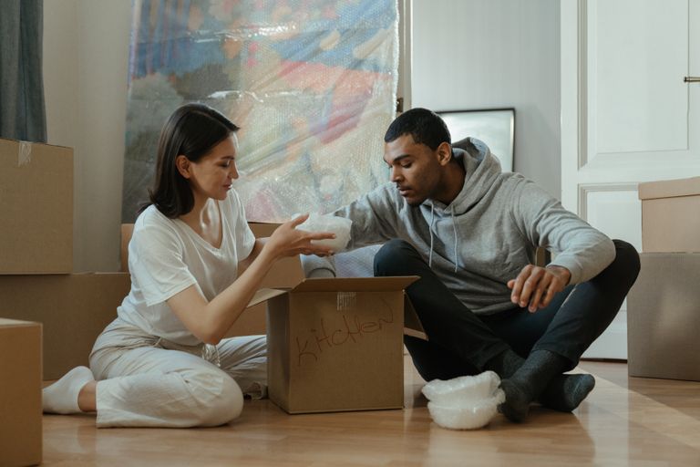 Young couple unpacking boxes in their new home, setting up kitchen items together.