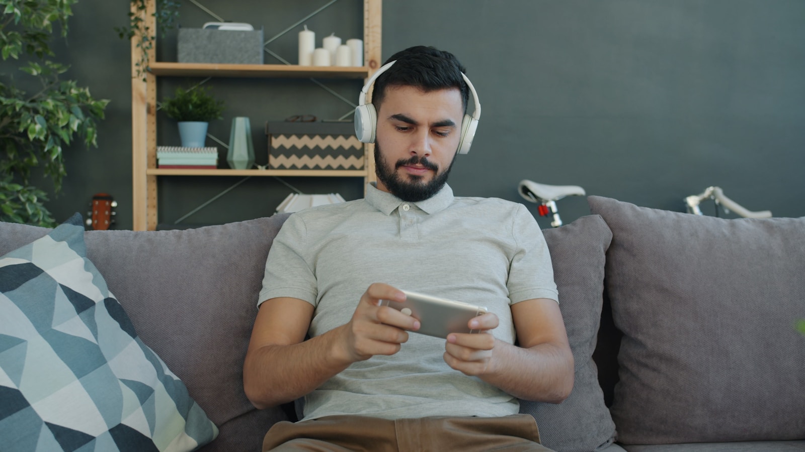 Man wearing headphones plays game on phone