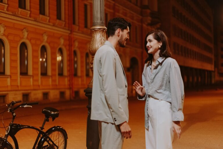A romantic couple having a conversation by a streetlight in the evening.