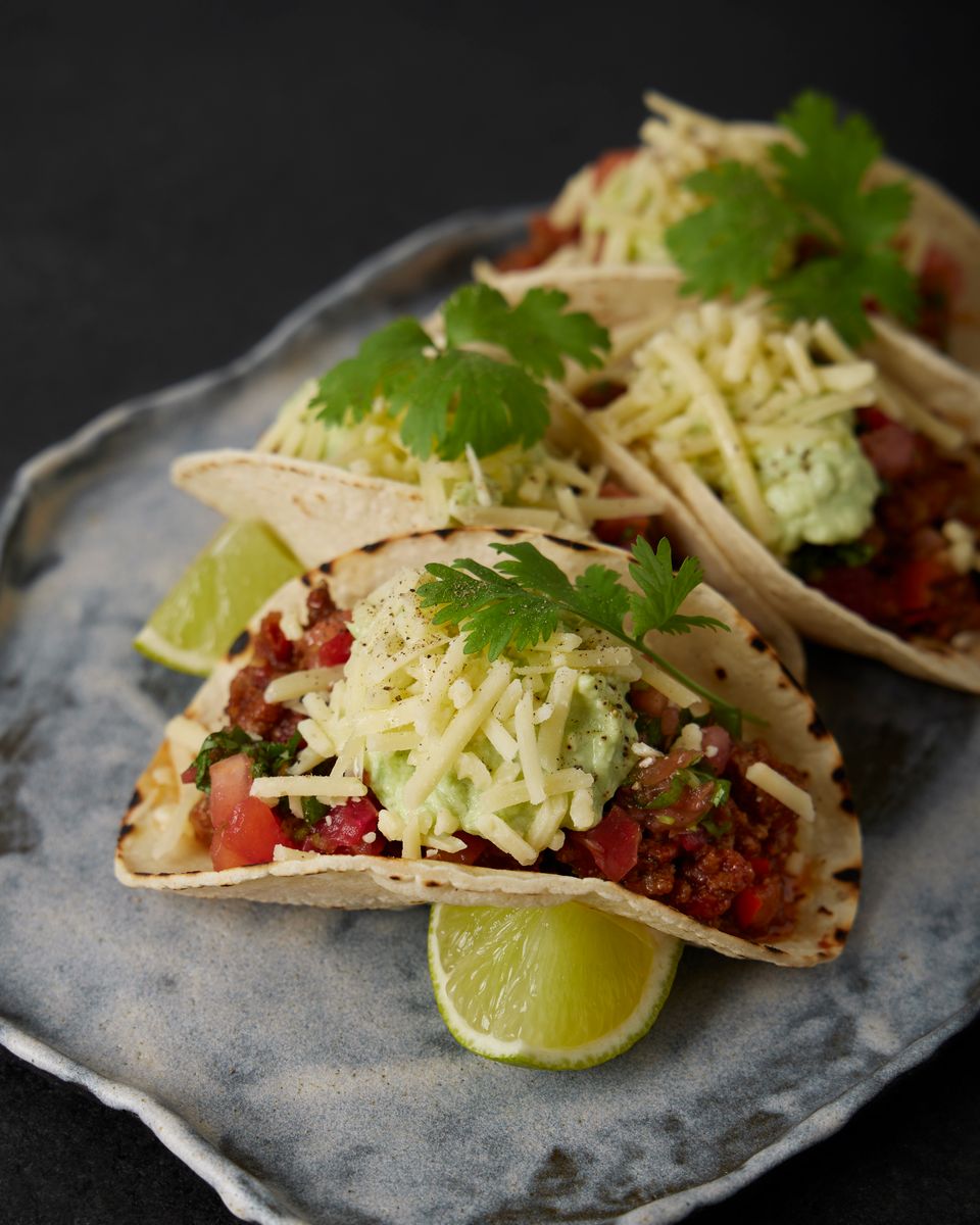 Mouthwatering tacos topped with cheese, salsa, and garnished with cilantro, ready to eat.