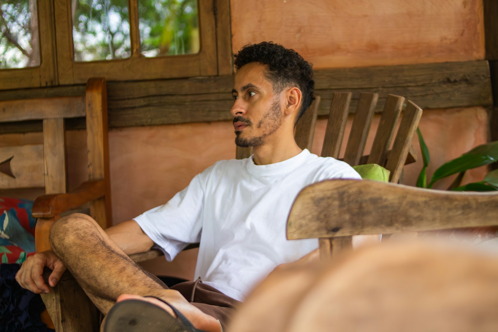 A man with a beard sits in a wooden chair