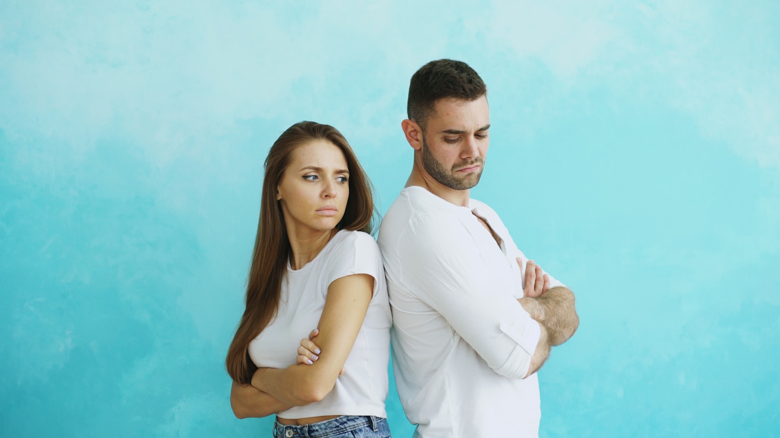 Couple standing back to back with arms crossed