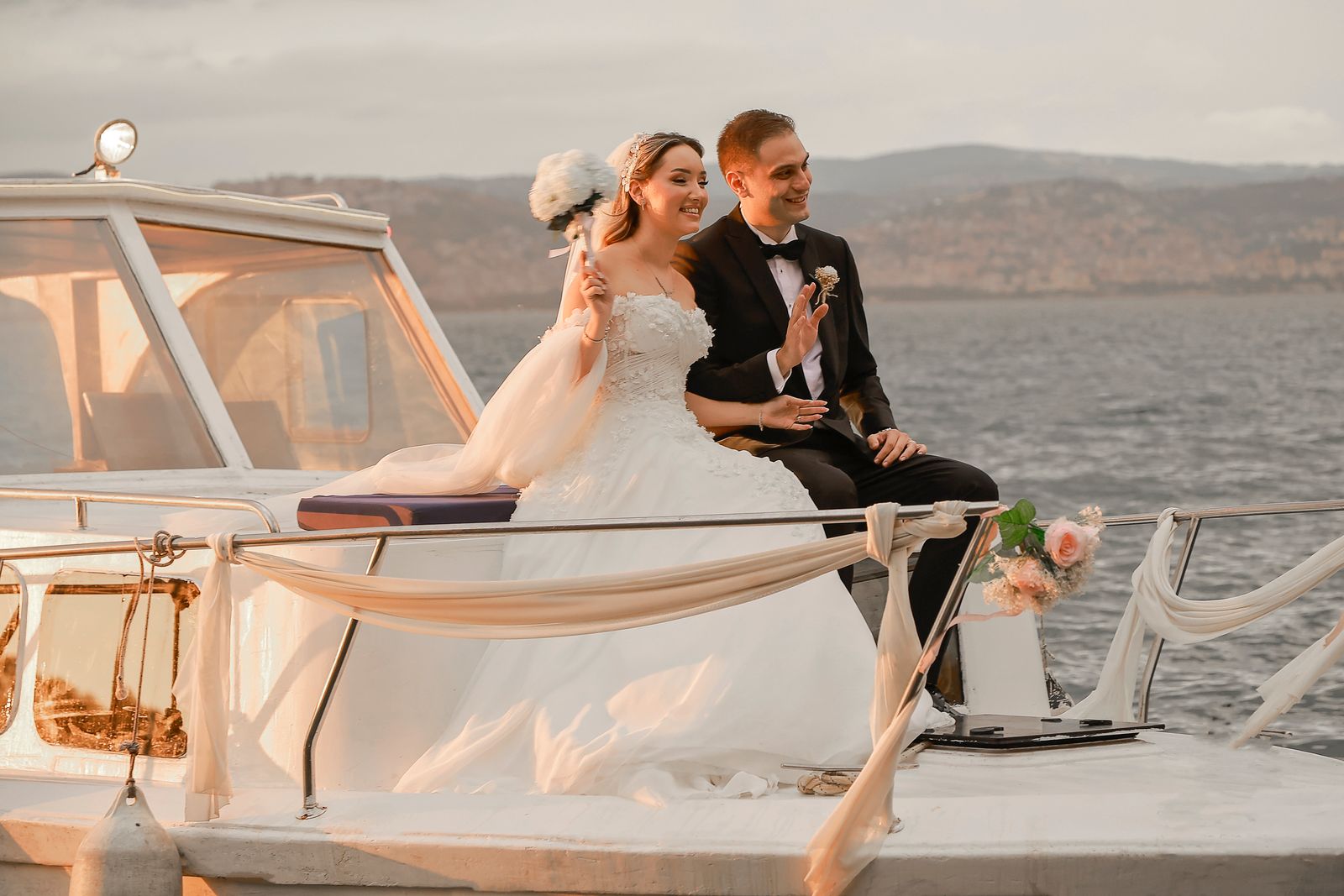 A joyful wedding couple on a yacht during sunset in Kocaeli, Türkiye.