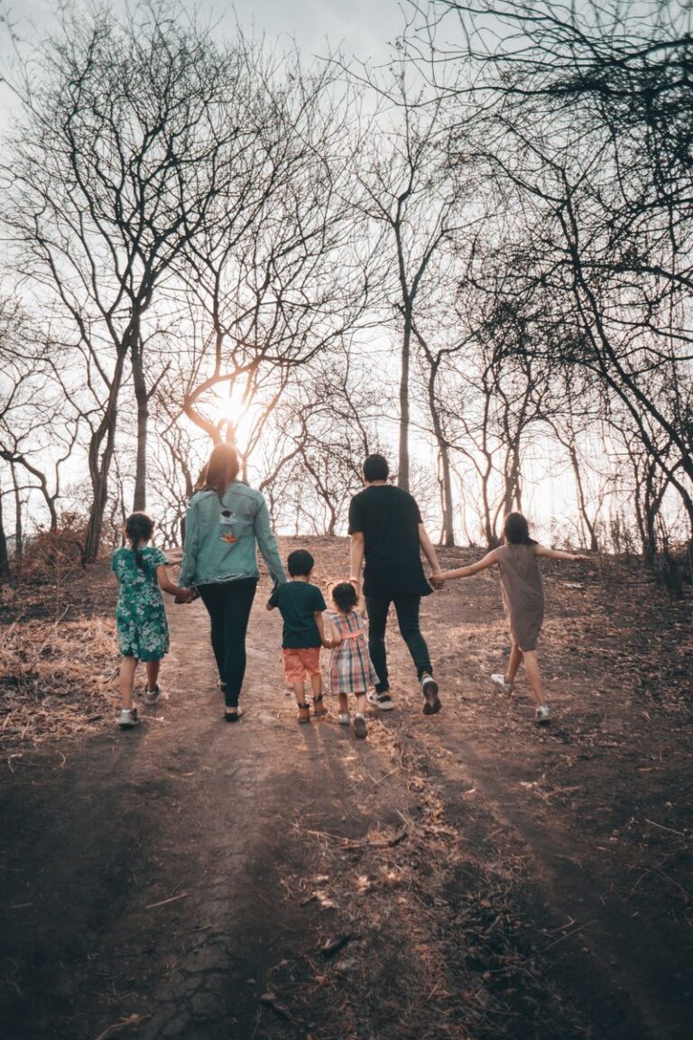 A family holding hands and walking along a bare path during a winter day, emphasizing unity and togetherness.