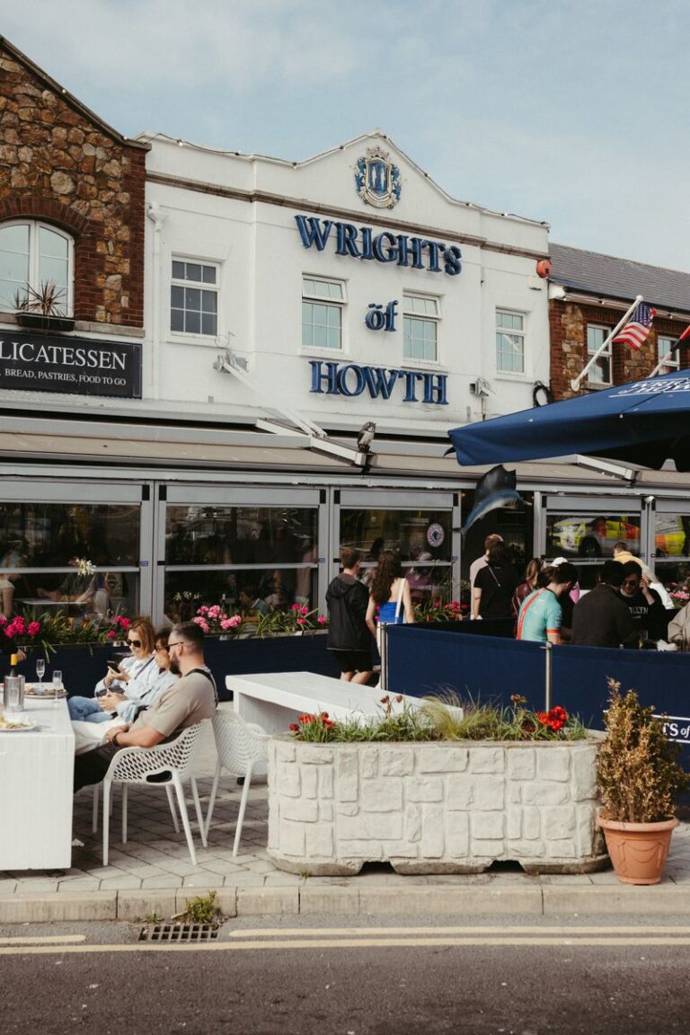 Lively outdoor dining scene at Wrights of Howth, Dublin, Ireland with people enjoying sunny weather.