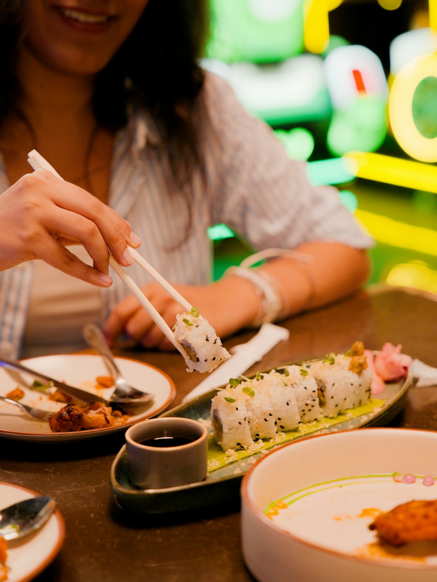 A person using chopsticks to lift a piece of sushi from a platter