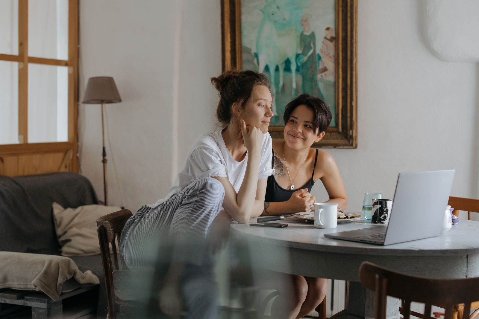 Two young women sharing a joyful conversation at home over breakfast.