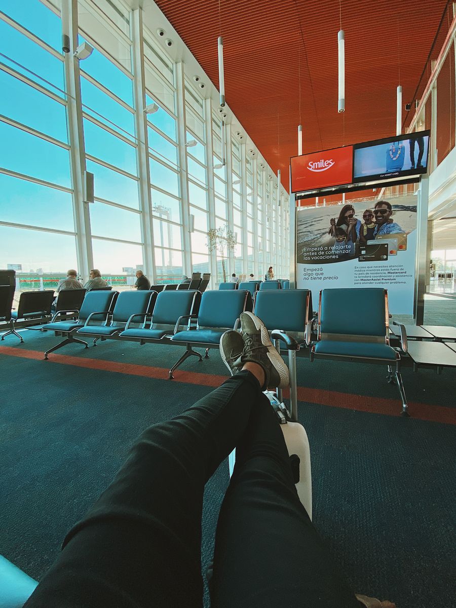 Crop anonymous male traveler with luggage waiting for departure in waiting room of modern airport