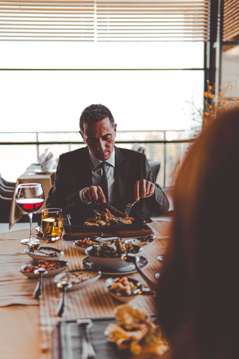 A man in a suit dining at a restaurant with wine, showcasing a formal and refined atmosphere.