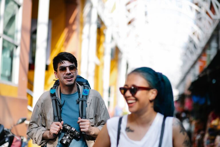 Joyful tourists walking through a colorful street market, capturing memories.