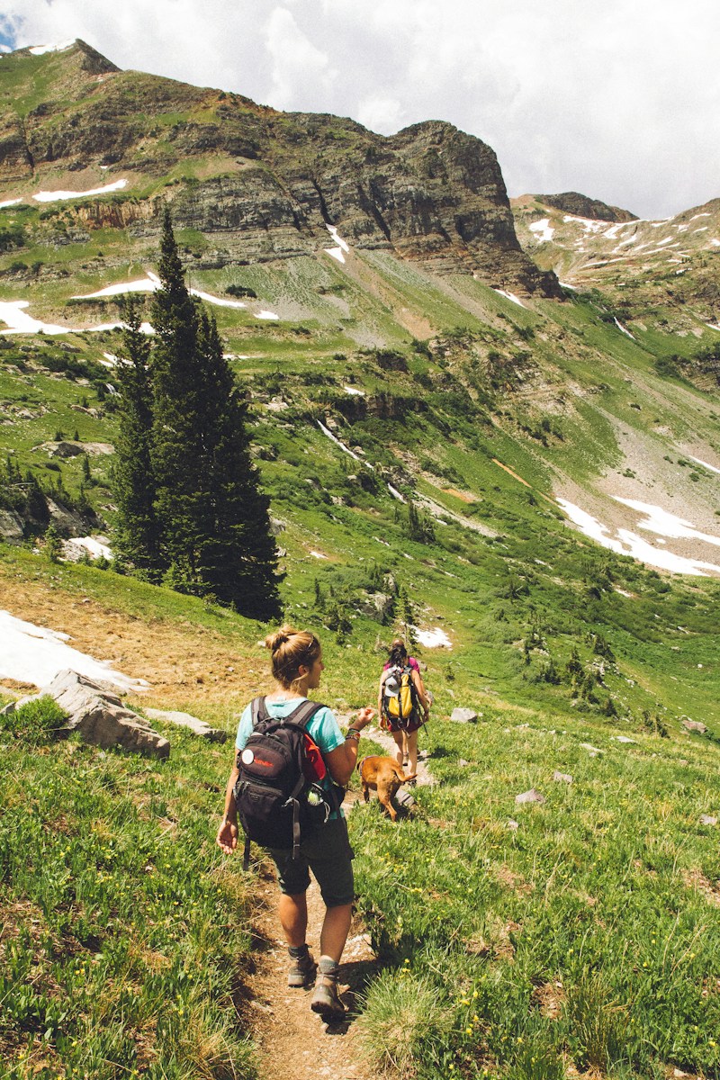 Two women hiking with a dog on a mountain trail in Crested Butte