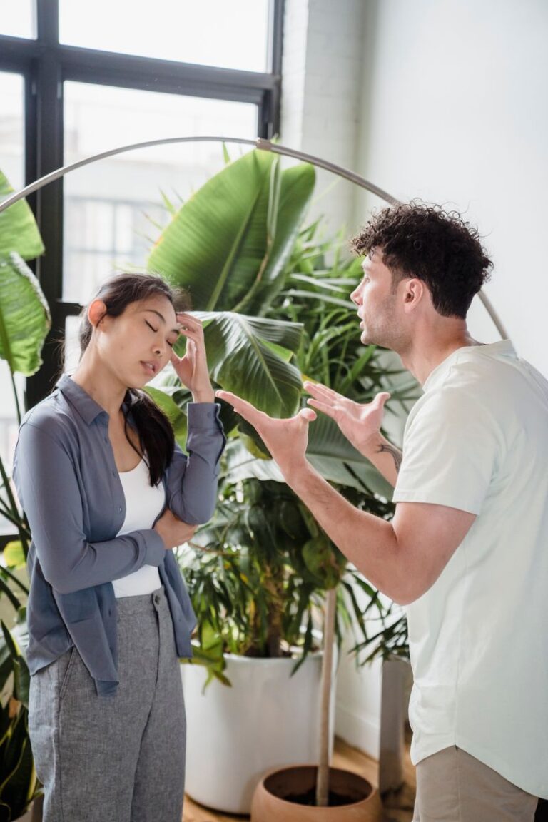 A man and woman having a heated argument indoors, surrounded by plants.