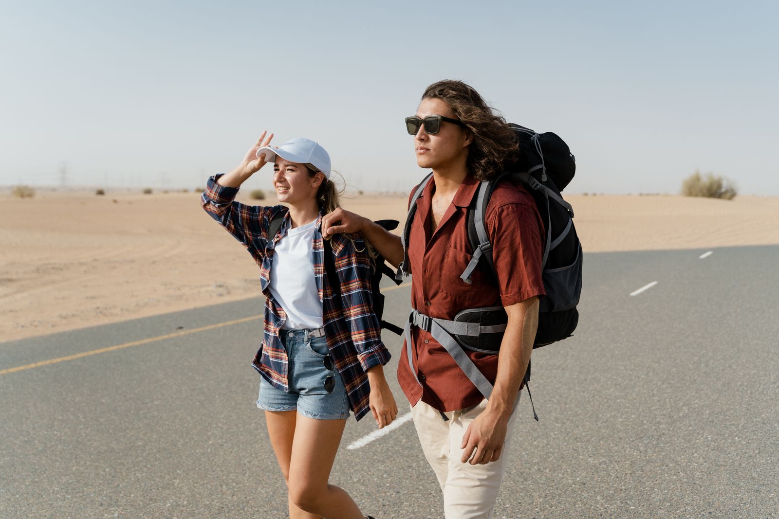 Young couple backpacking through a desert road, capturing wanderlust and exploration.