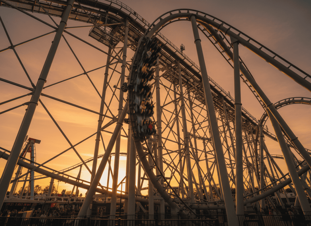 A roller coaster train banking through a zero-gravity inversion at sunset