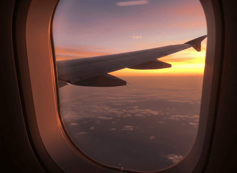 Airplane wing silhouetted against an orange sunset sky during a flight