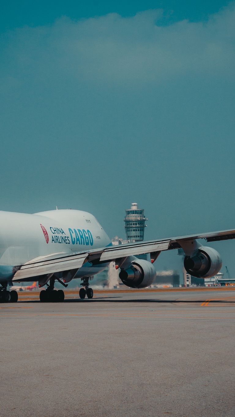 A cargo airplane on the tarmac near an airport control tower, ready for takeoff.