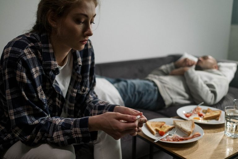 A couple in an intimate home setting reflecting on life's challenges, symbolized by untended breakfast.