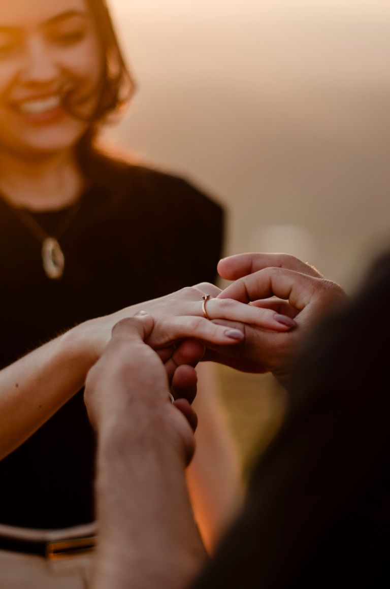 A couple shares a heartfelt engagement moment during a sunset proposal.