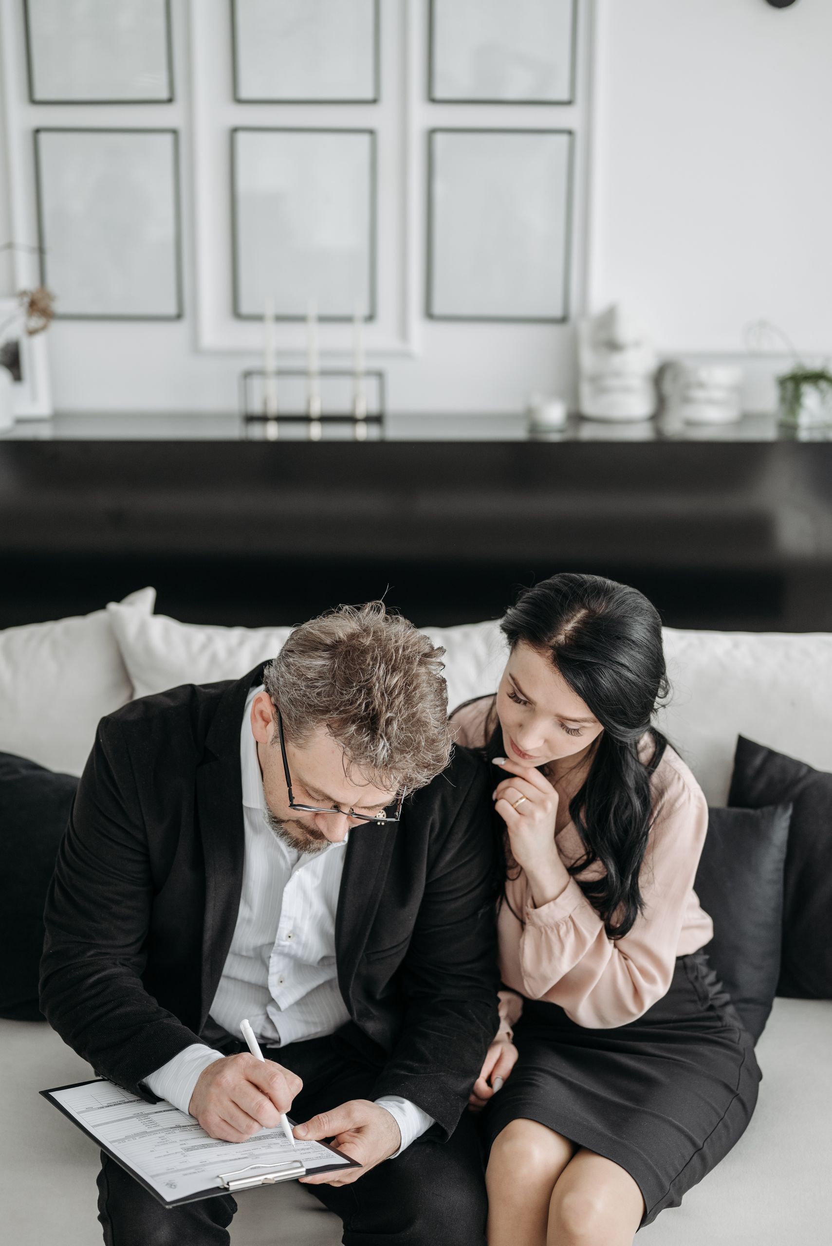 A couple sitting on a sofa reviewing documents, indicating a decision-making process.