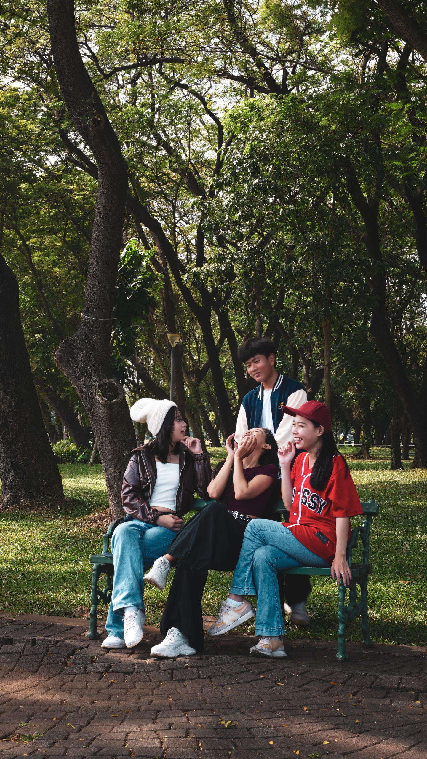 A group of teenagers having a fun day at a park in Jakarta, Indonesia. Trees and greenery surround them.