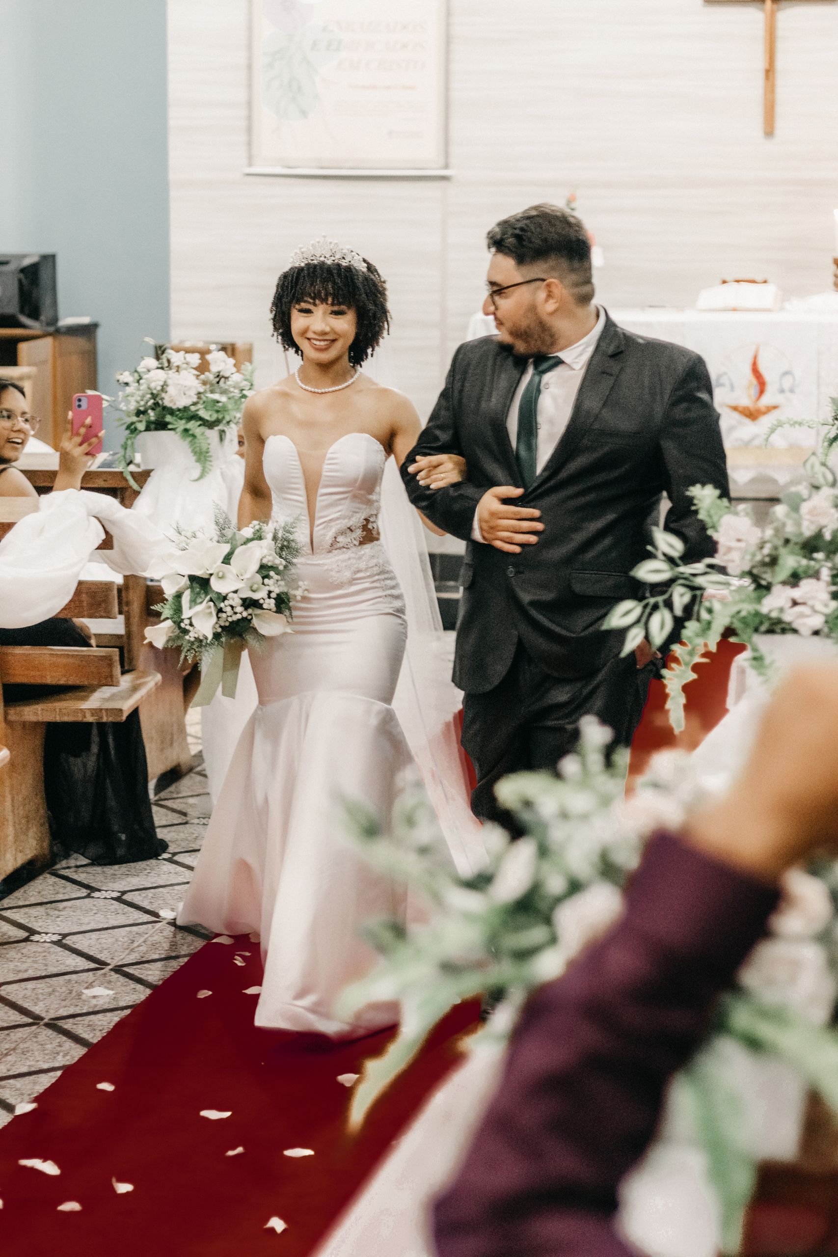 A joyful bride and groom walking down the aisle in a beautifully decorated church setting.