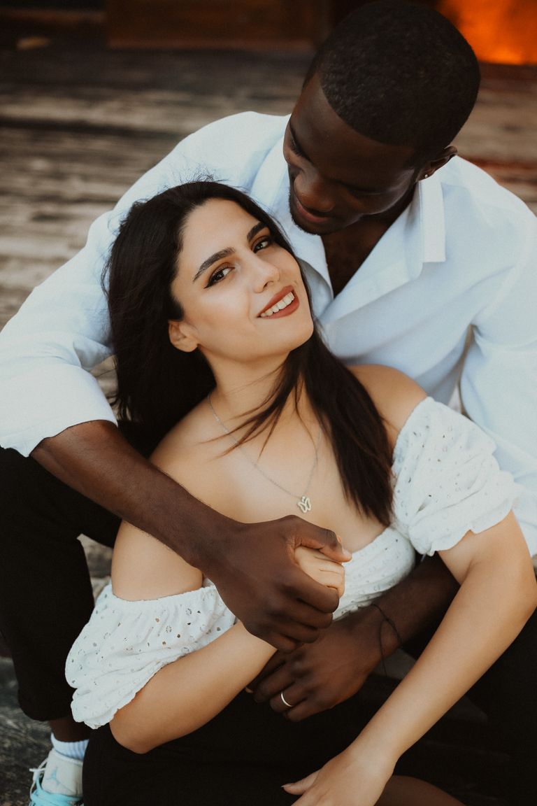 A loving couple embracing while seated outdoors, exuding warmth and togetherness.
