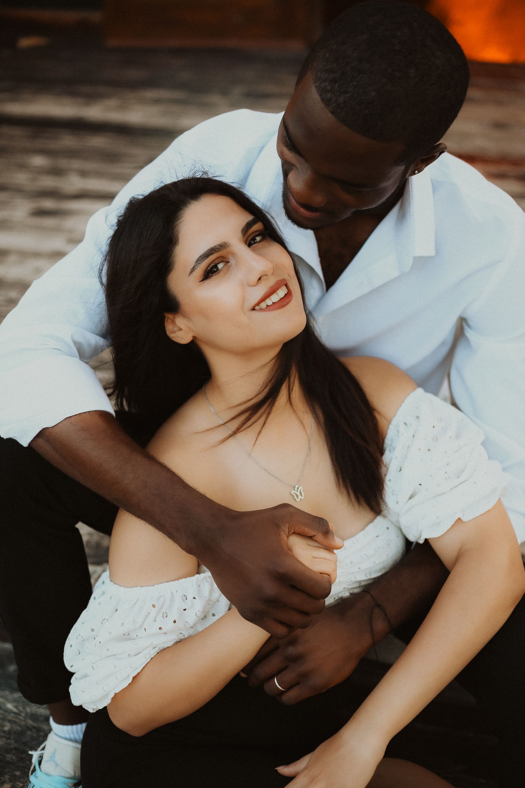 A loving couple embracing while seated outdoors, exuding warmth and togetherness.