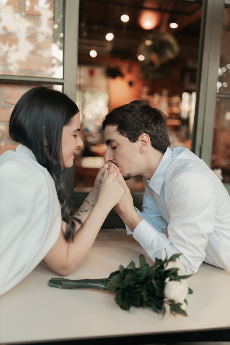 A romantic scene of a loving couple holding hands at a cozy cafe indoors.