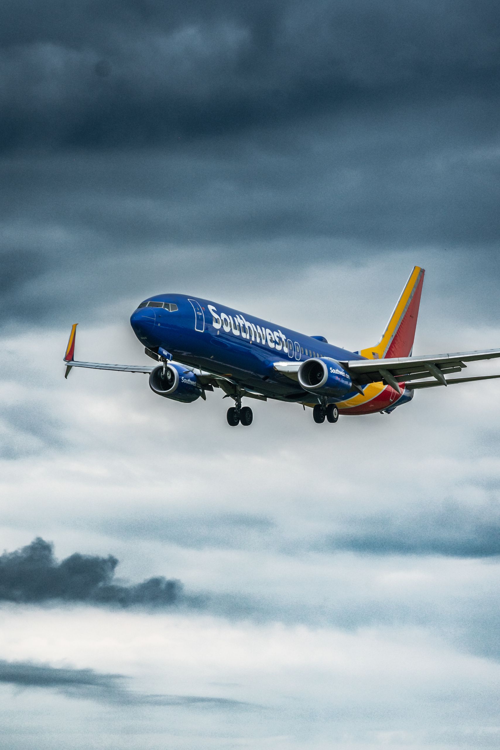 A Southwest Airlines plane flying in a dramatic cloudy sky, showcasing dynamic weather conditions.