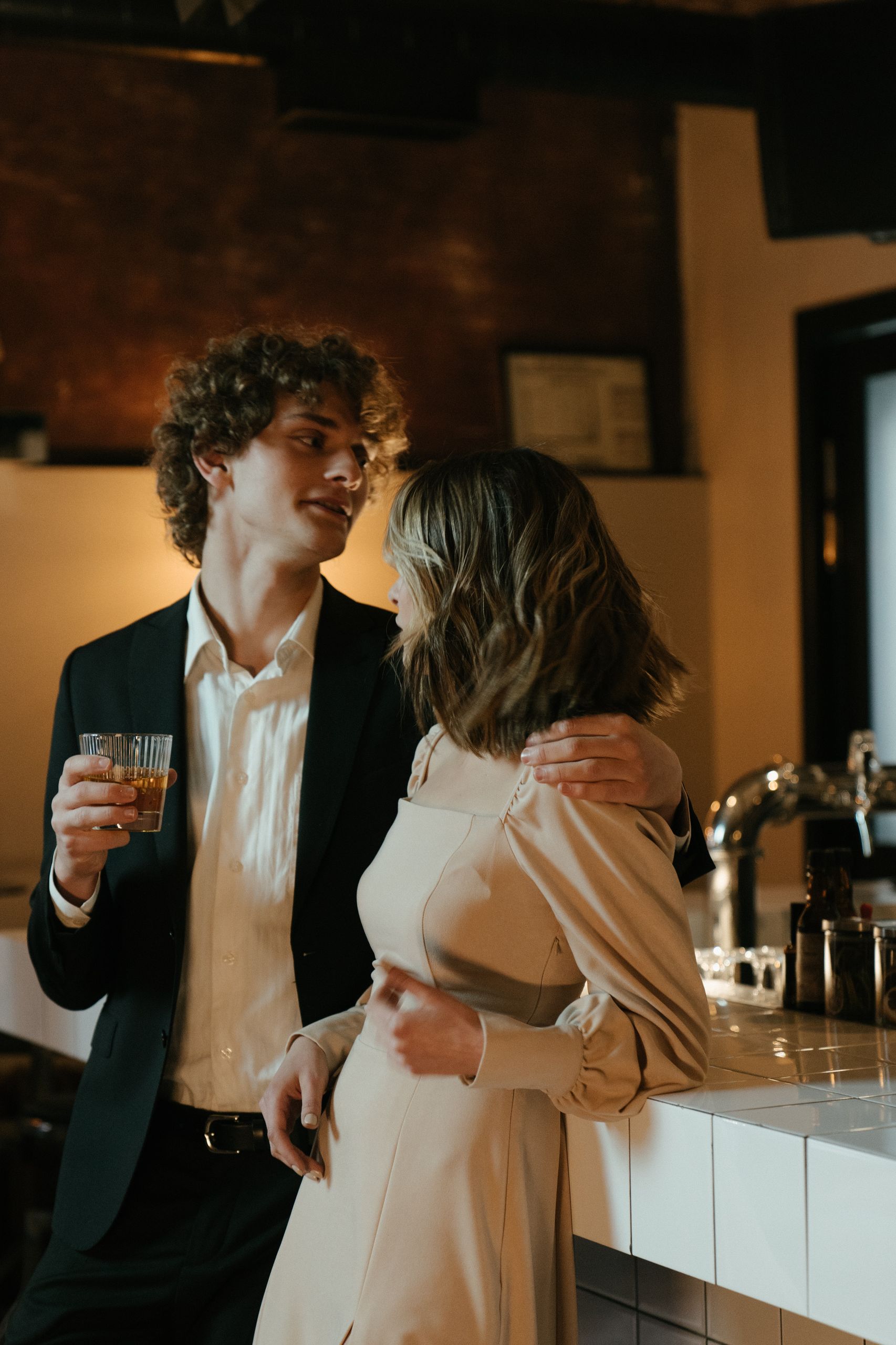 A stylish couple enjoys a romantic moment at an elegant bar setting.
