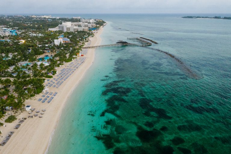 A tranquil aerial view of a beachfront resort, white sandy beach, and an extensive pier stretching into the turquoise sea.