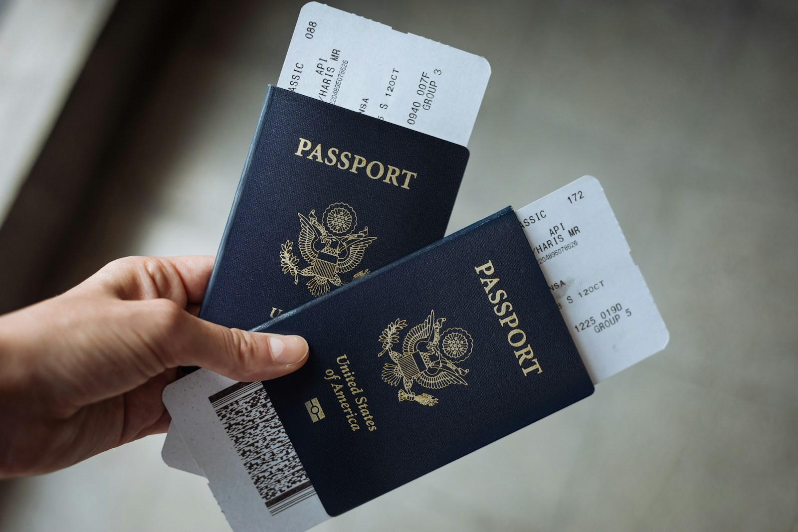 A hand holding two United States passports with airline boarding passes tucked inside