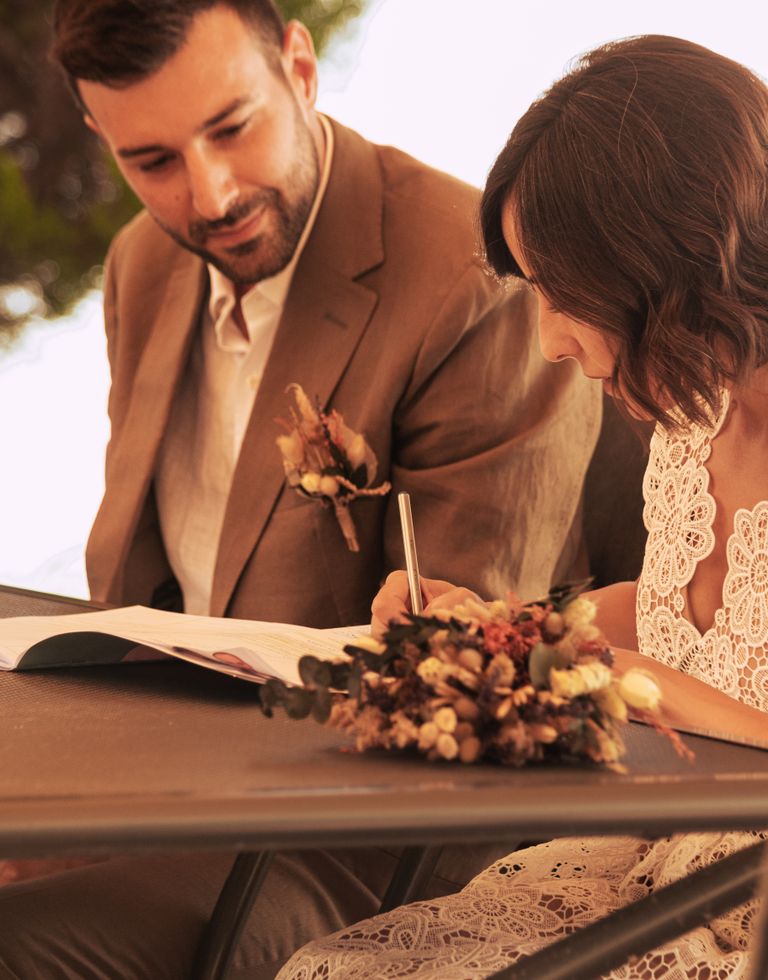 Bride and groom signing documents during their wedding ceremony, elegantly dressed in Tirana, Albania.