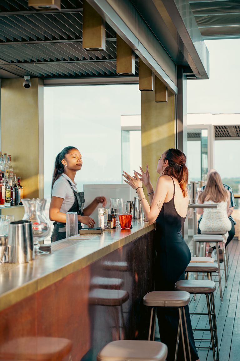 Casual rooftop bar with friends enjoying drinks on a sunny day.