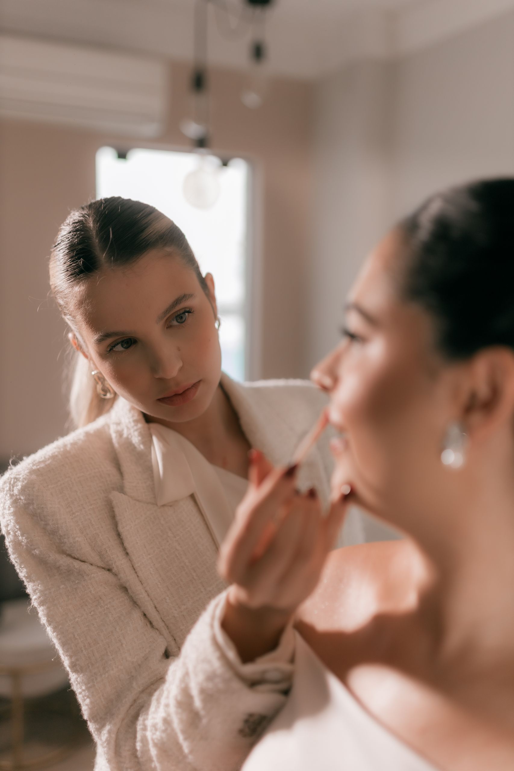 Close-up of a makeup artist meticulously applying lipstick to a bride before her wedding ceremony.