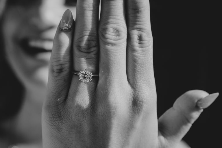 Close-up of woman's hand displaying engagement ring, exuding happiness.