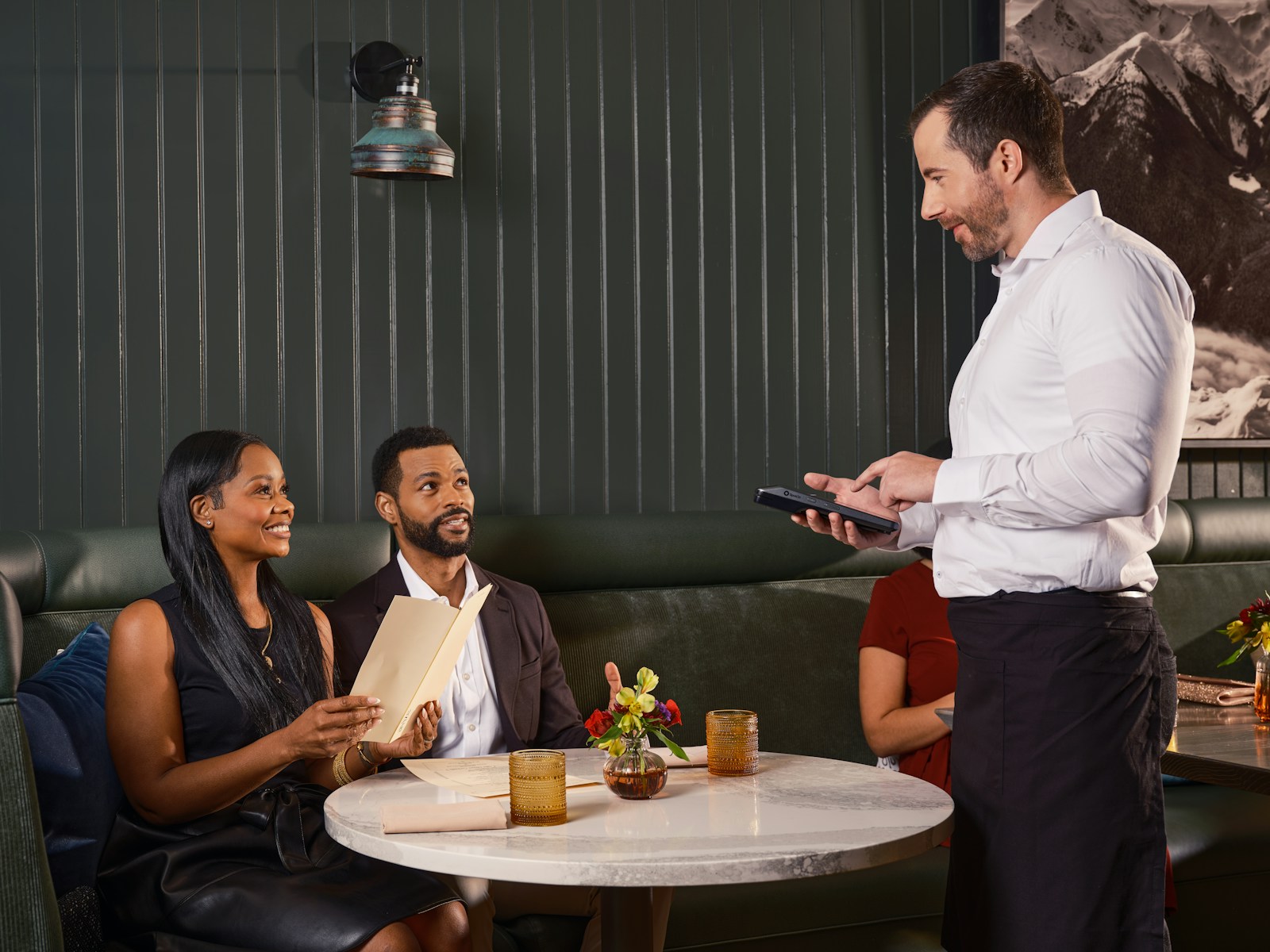 Waiter taking order from couple in restaurant