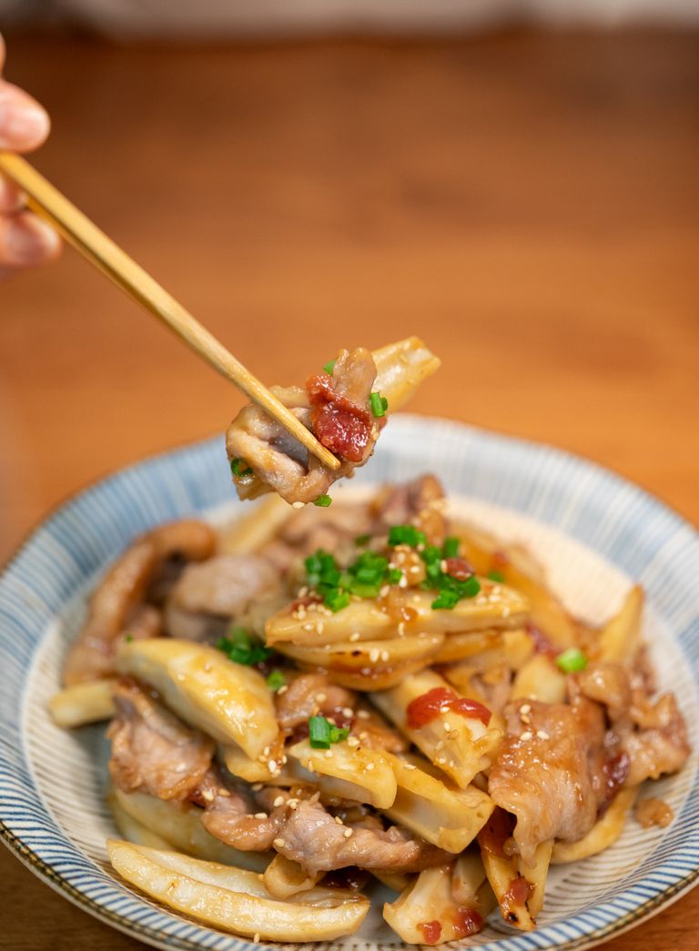Delicious stir-fried Asian noodles with tender pork and vegetables, garnished with sesame seeds and green onions.