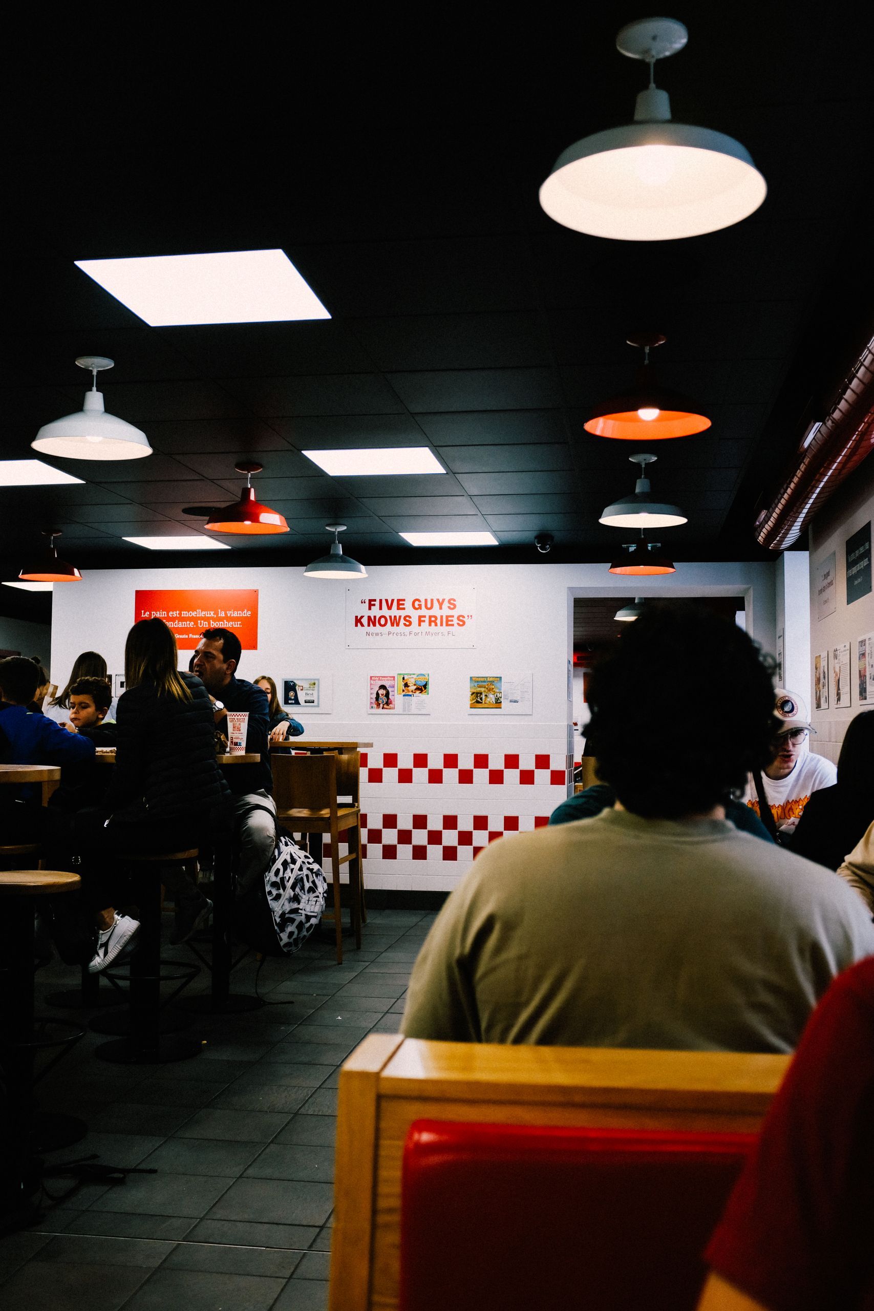 Diners enjoying their meals in a warmly lit Five Guys restaurant, embodying a friendly and inviting atmosphere.