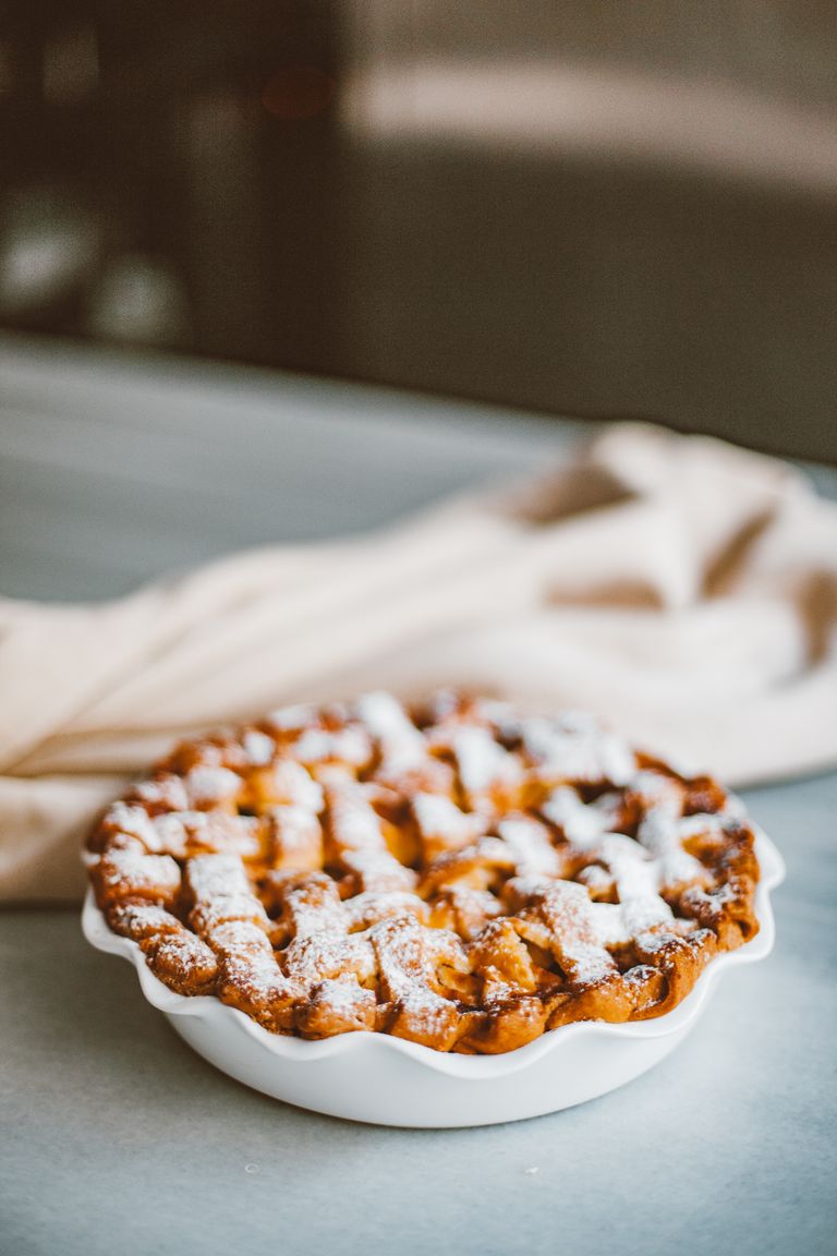 Freshly baked homemade apple pie with lattice crust and powdered sugar on a plate.