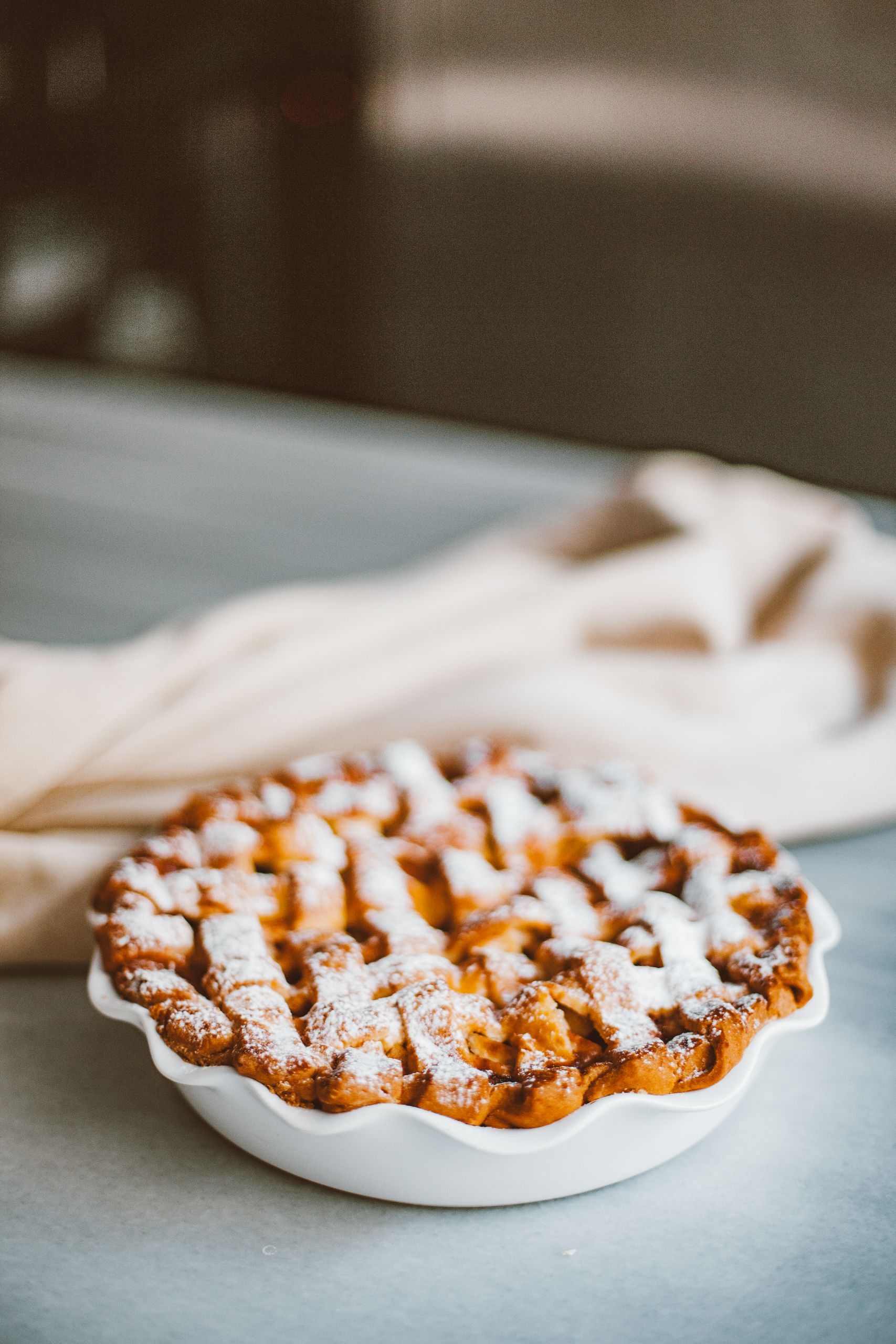 Freshly baked homemade apple pie with lattice crust and powdered sugar on a plate.