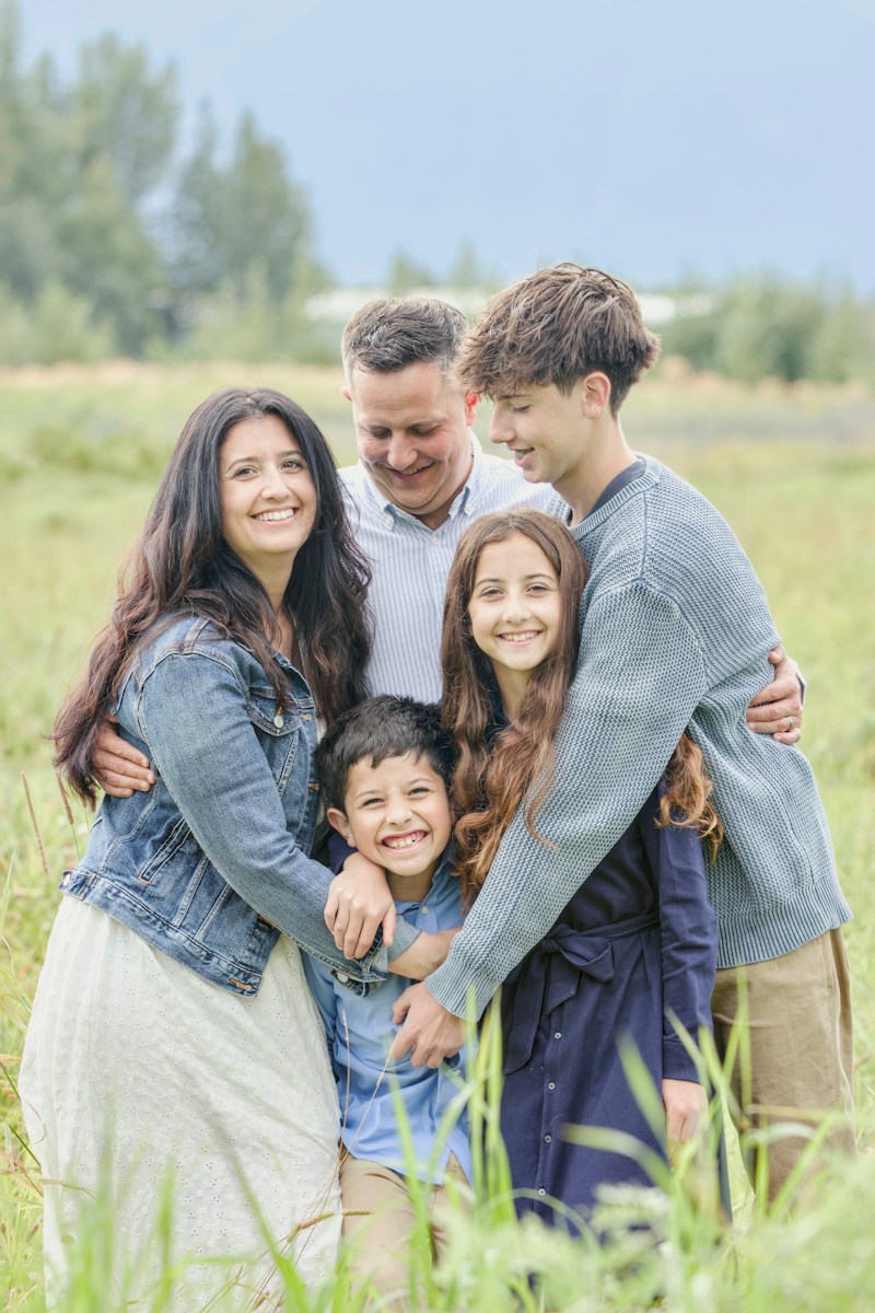 A happy family of five posing in a grassy field