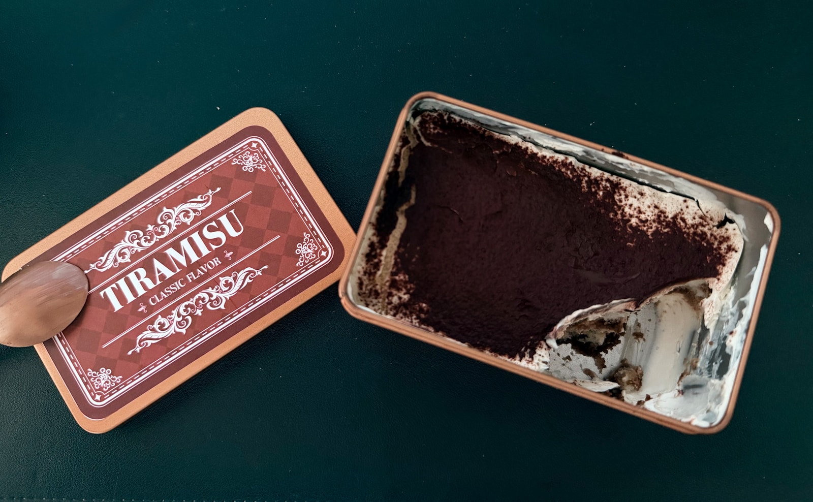 Partially eaten tiramisu in a container with its lid
