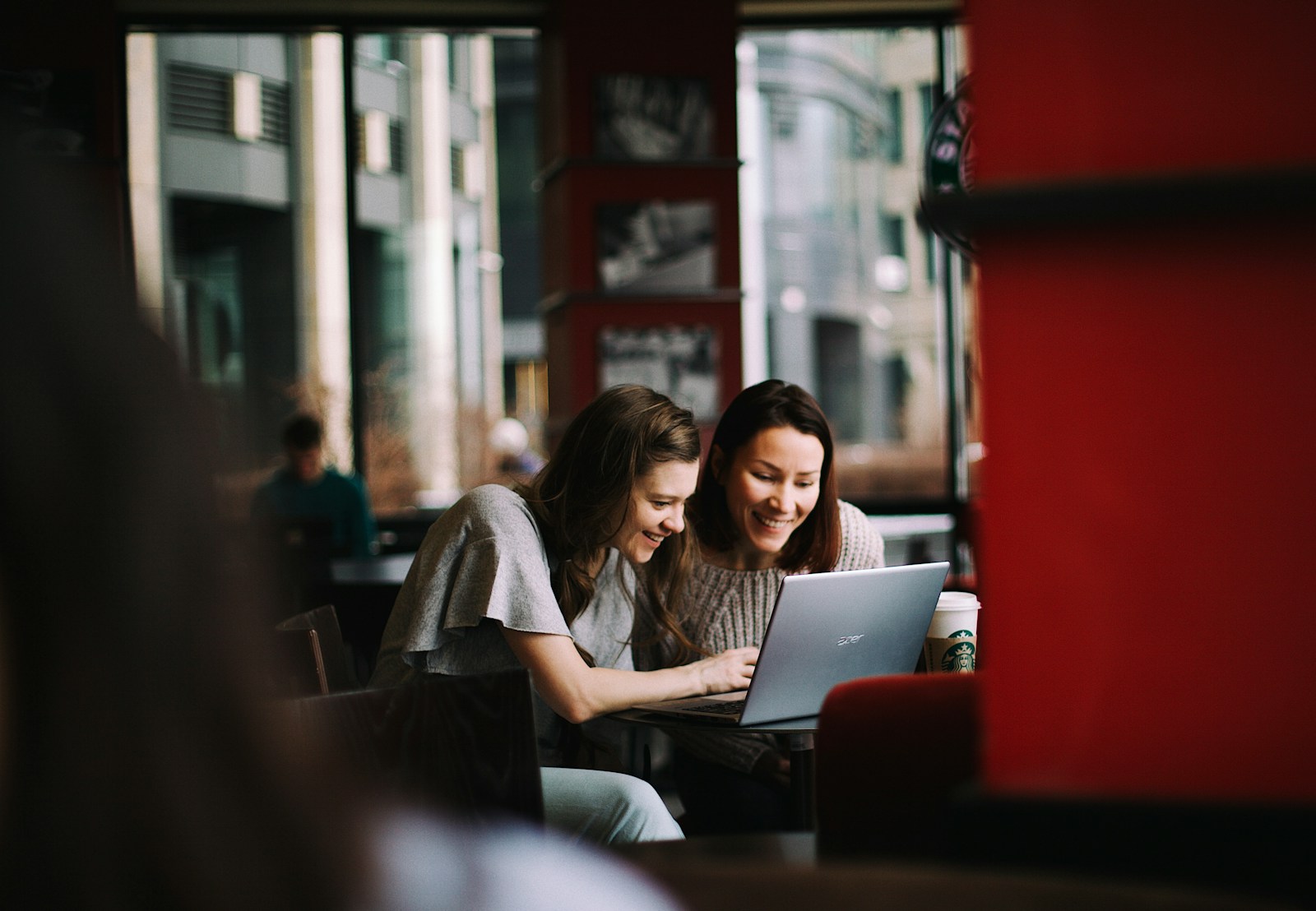 Two women looking at a laptop screen together in a cafe