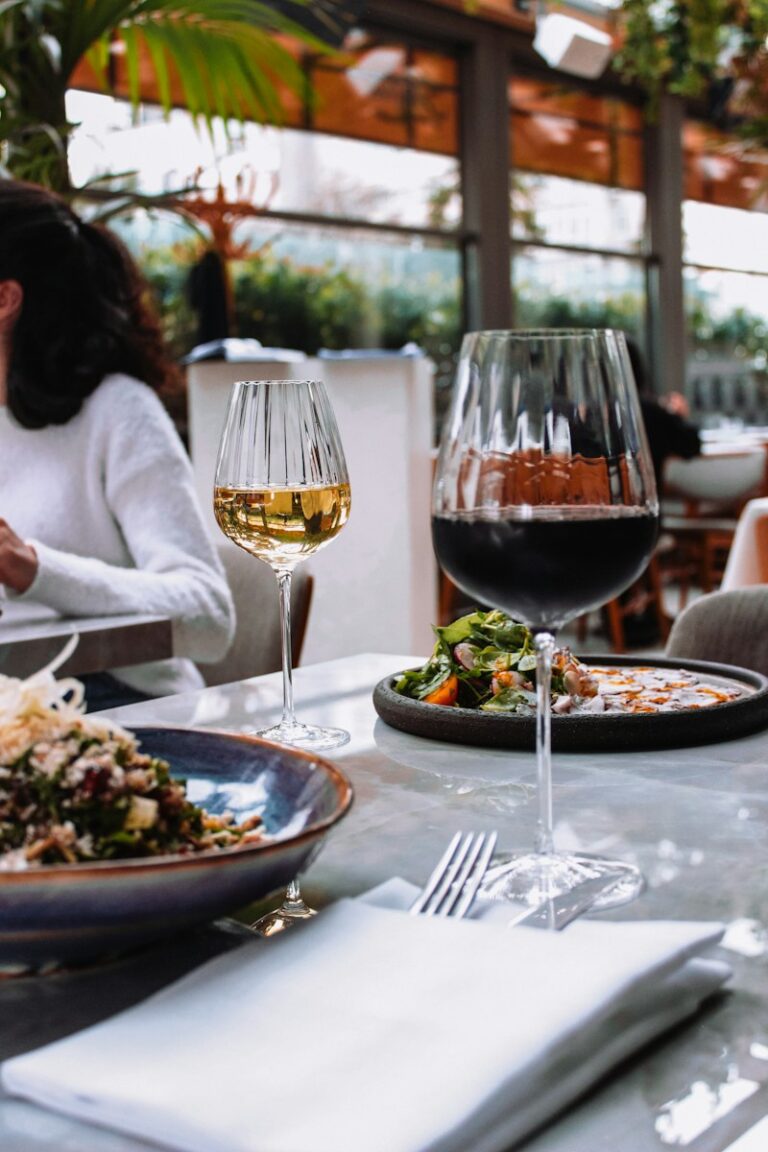 a woman sitting at a table with a plate of food and a glass of wine