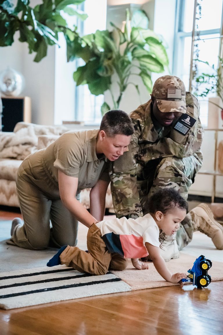 Interracial family enjoying playtime indoors with a young child and toy.