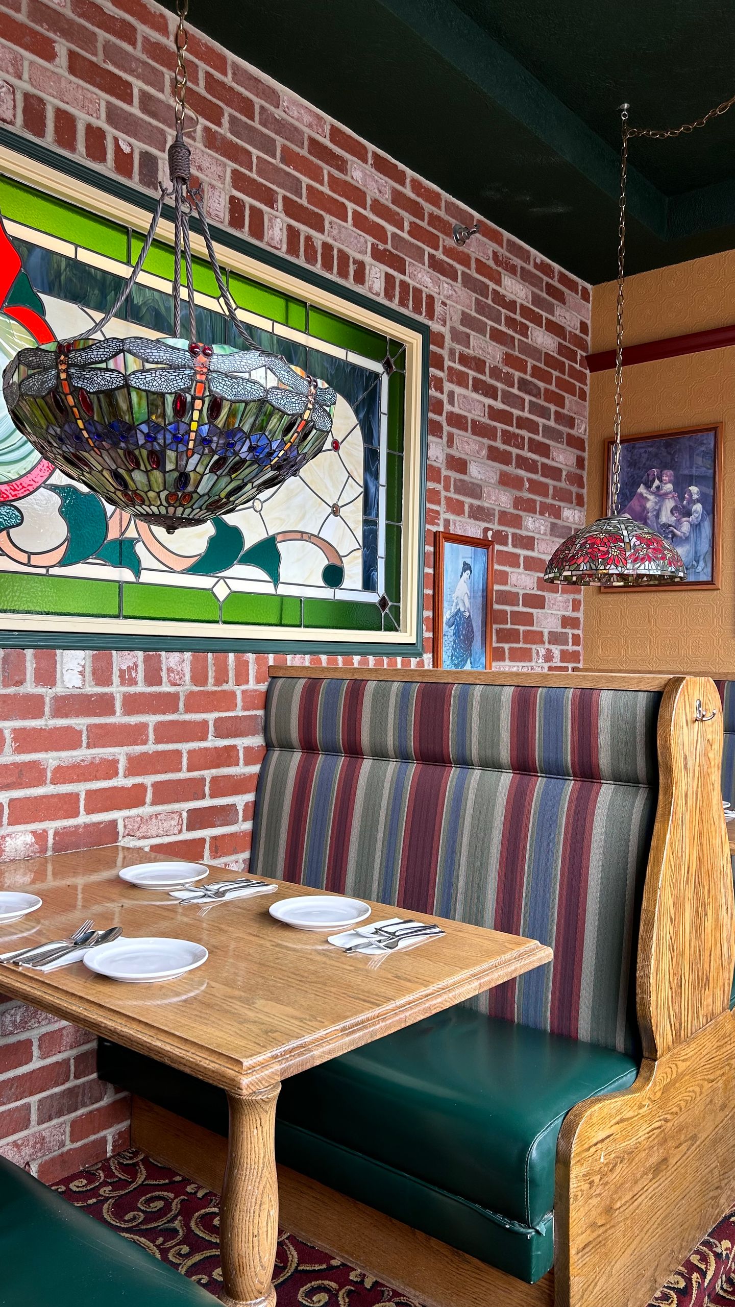 Inviting restaurant booth featuring stained glass window and vintage decor.