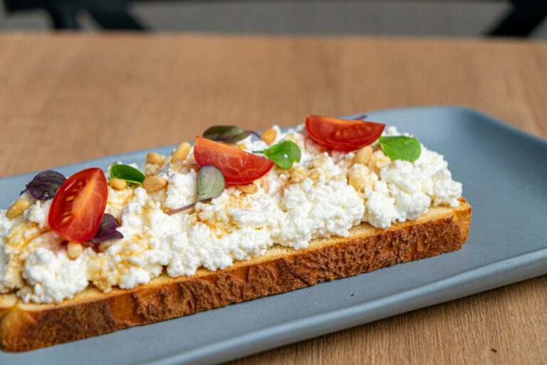 a blue plate topped with a piece of bread covered in cheese and veggies